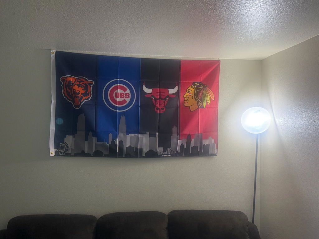 Real customer photo of the Chicago four-team skyline flag hanging above a sofa