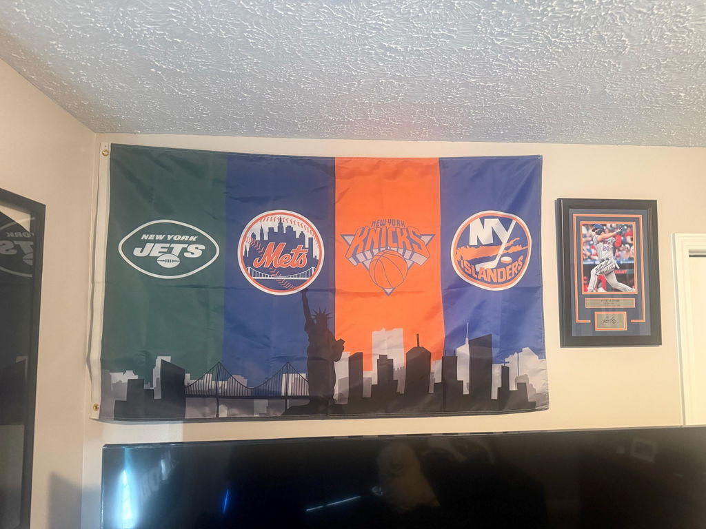 Customer photo of a custom New York four-team skyline flag above a television