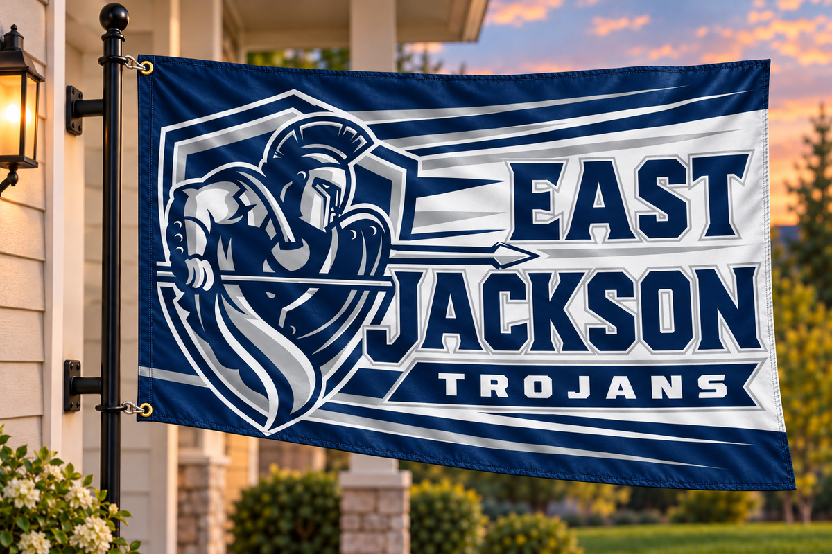 East Jackson Trojans flag mockup with both left grommets clipped directly to house-mounted pole