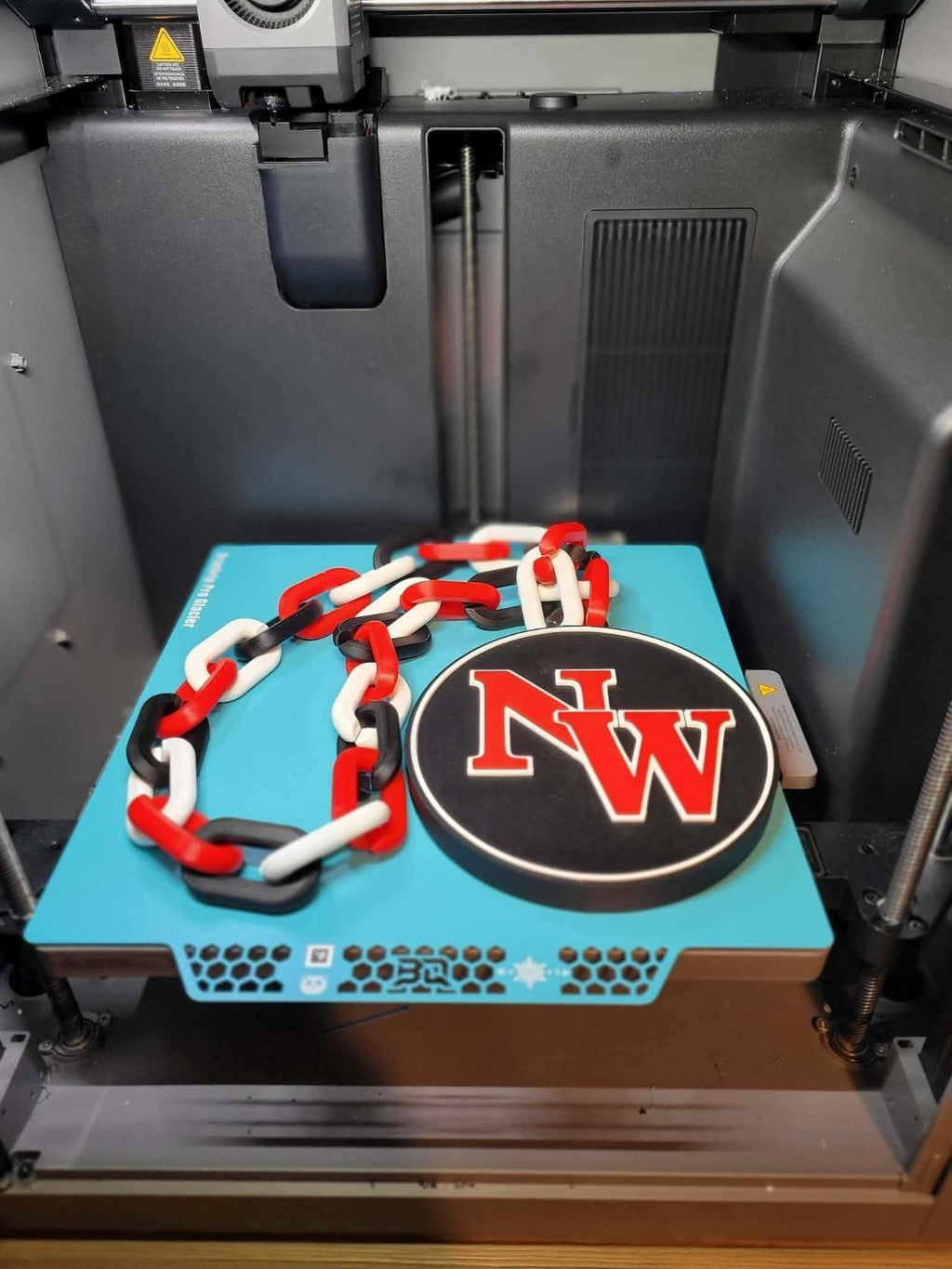Actual Northwest Mounties 3D-printed hype chain with black circular NW pendant and red, white and black links.